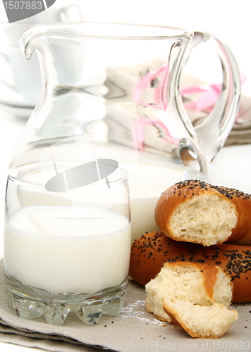 Image of Bagel with poppy seeds a pitcher of milk.