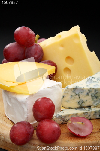 Image of Cheese and grapes on a wooden board.