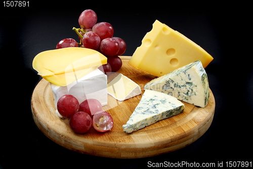 Image of Cheese and grapes on a wooden board.