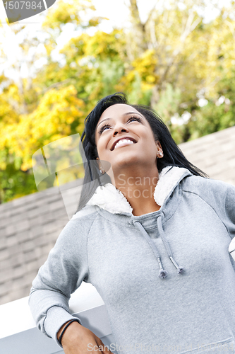 Image of Smiling young woman outdoors looking up