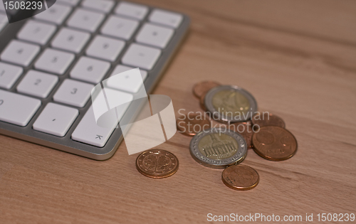 Image of Keyboard and euro coins on wooden desk