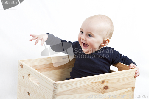 Image of young child in wooden box pointing to the left