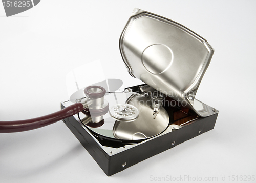 Image of opened hard disk with stethoscope on grey background