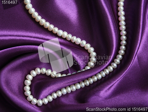 Image of White pearls on a lilac silk as background 