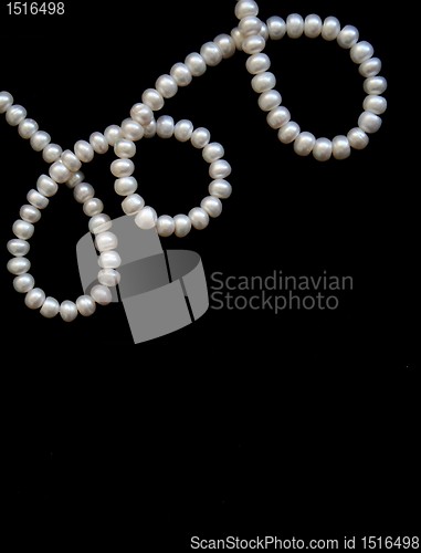 Image of White pearls on the black silk as background 