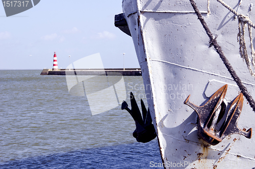 Image of Ship with raised anchor closeup and red lighthouse