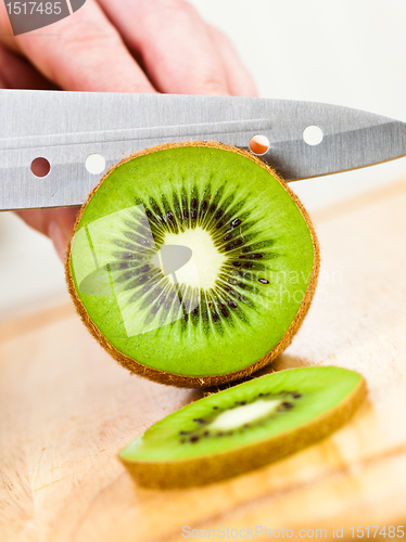 Image of Woman's hands cutting kiwi