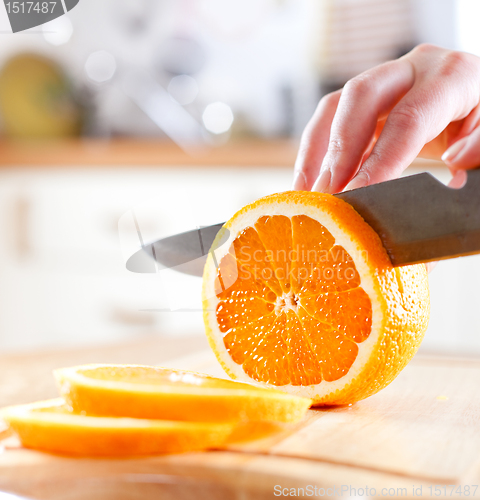 Image of Woman's hands cutting orange