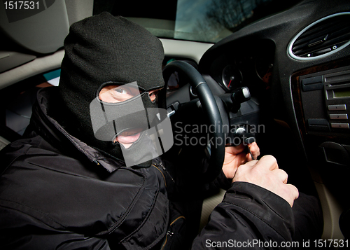 Image of robber and the thief in a mask hijacks the car