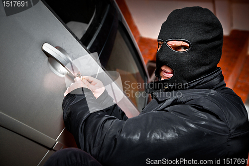 Image of robber and the thief in a mask hijacks the car