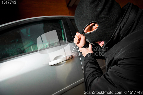 Image of robber and the thief in a mask hijacks the car