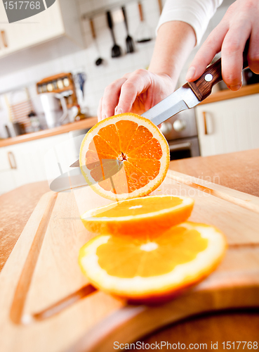 Image of Woman's hands cutting orange