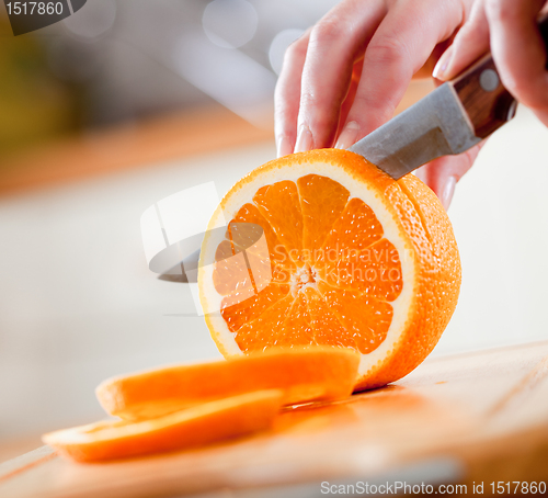 Image of Woman's hands cutting orange