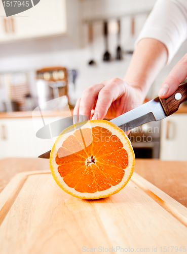 Image of Woman's hands cutting orange