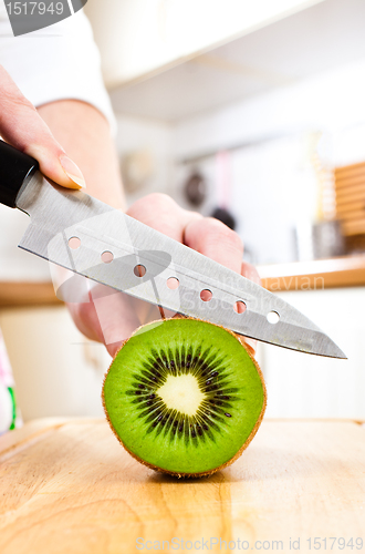 Image of Woman's hands cutting kiwi