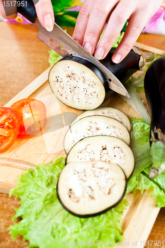 Image of Woman's hands cutting aubergine eggplant