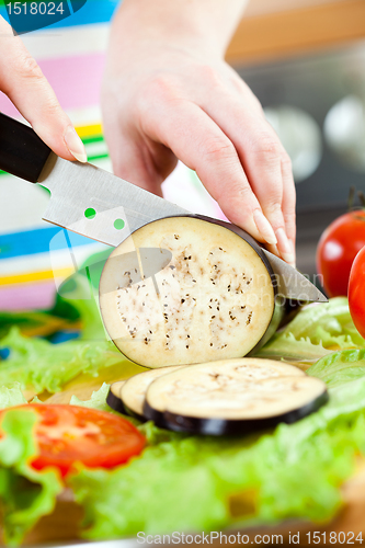 Image of Woman's hands cutting aubergine eggplant