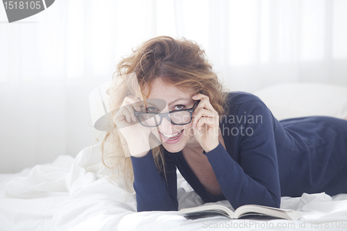 Image of woman in bed holding glasses 