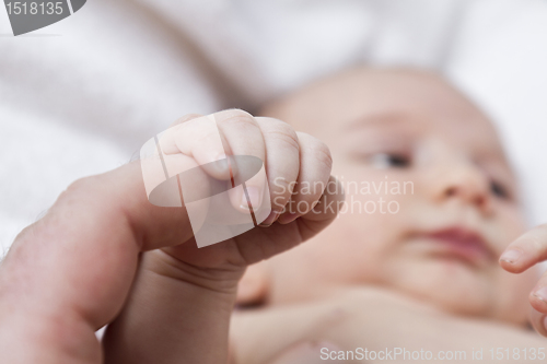 Image of nursling holding finger of adult person