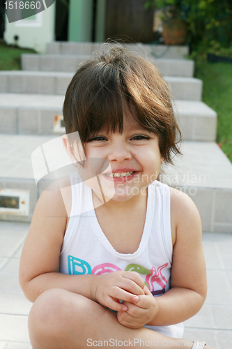 Image of Beautiful girl sitting outdoors smilling