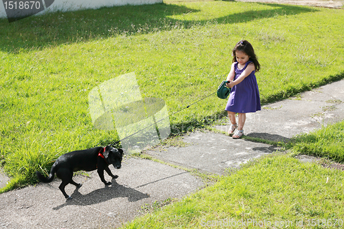 Image of Little girl having trouble with her dog in the park