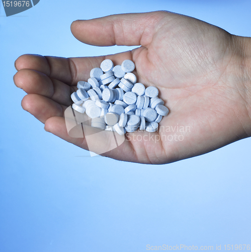 Image of hand holding blue pills