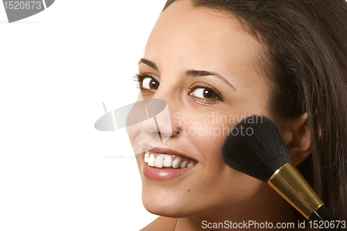 Image of young woman applying blusher