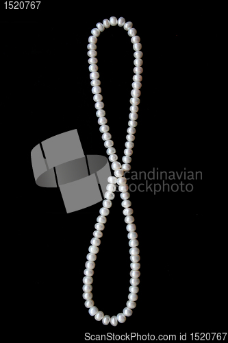 Image of White pearls on the black silk as background 