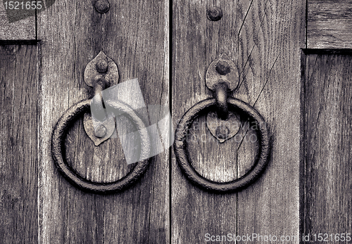 Image of ancient wooden gate with door knocker rings