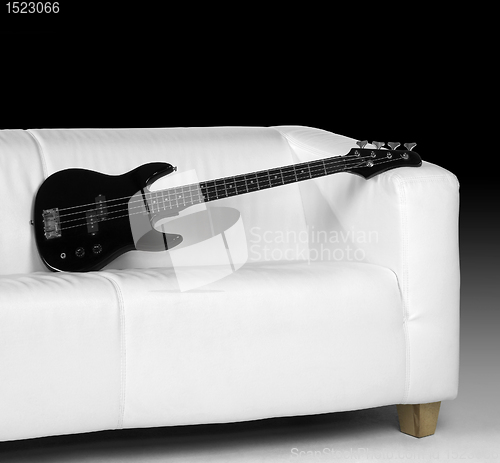 Image of black bass guitar and white couch
