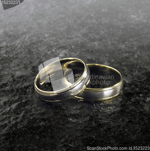 Image of two golden wedding rings on stone surface