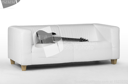 Image of black bass guitar on white couch