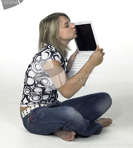 Image of cute blonde girl kissing her laptop