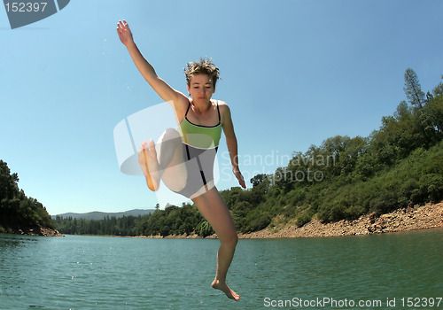Image of Young woman jumping in the lake