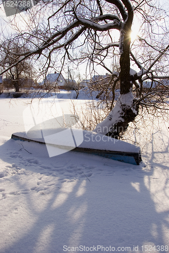 Image of Old wooden boat covered with snow.