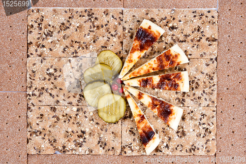 Image of still life of bread, slices of pickles and cheese.