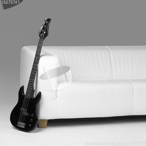 Image of black bass guitar and white couch