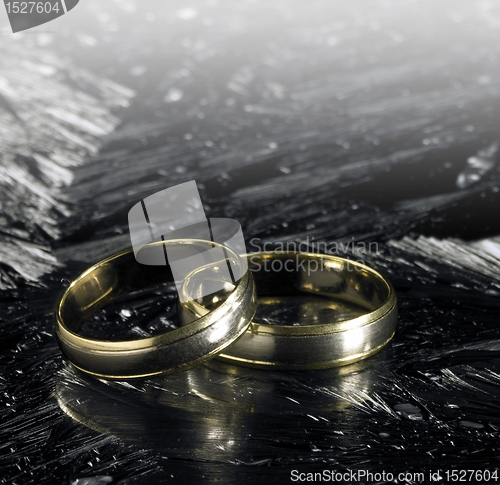 Image of two golden wedding rings on ice surface