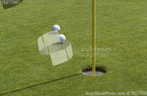 Image of hole and golf balls in green back