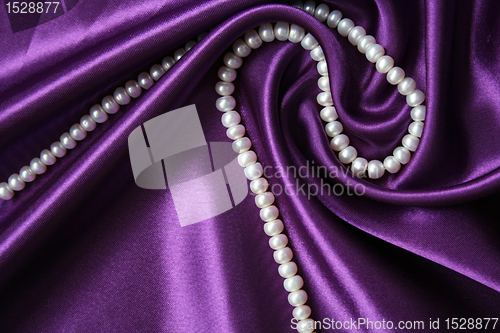 Image of White pearls on a lilac silk as background 