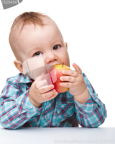 Image of Little child is eating red apple