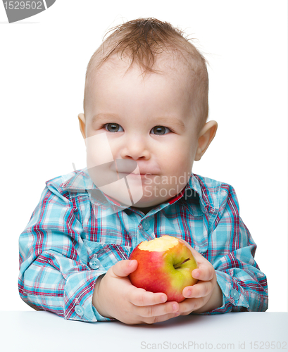 Image of Little child is eating red apple