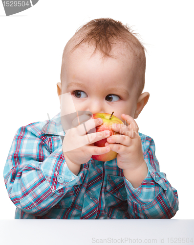 Image of Little child is eating red apple
