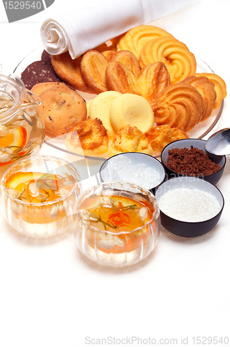 Image of floral tea set and pastry assortment over white