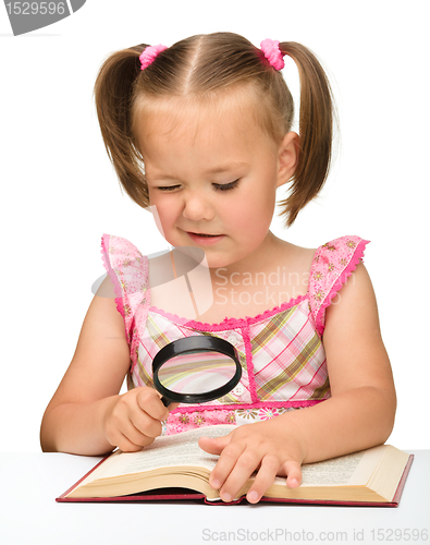 Image of Little girl play with book and magnifier