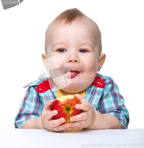 Image of Little child is eating red apple