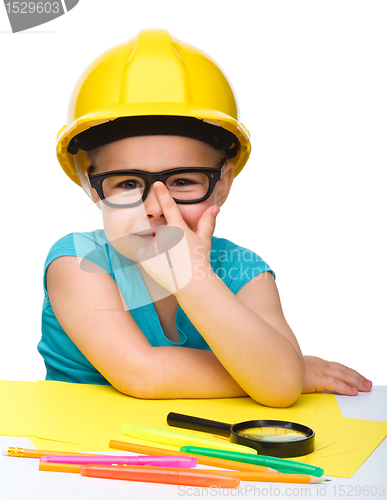 Image of Cute little girl is playing while wearing hard hat