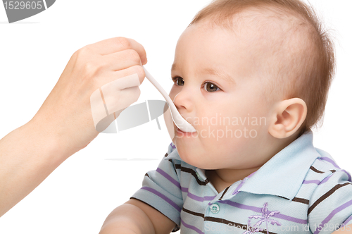 Image of Little boy is being feed by his mother