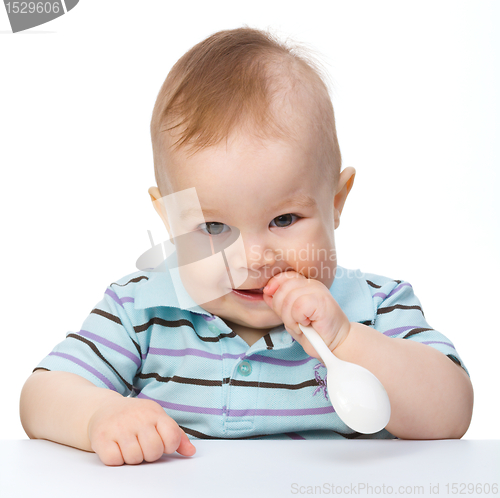 Image of Cute little boy is biting spoon