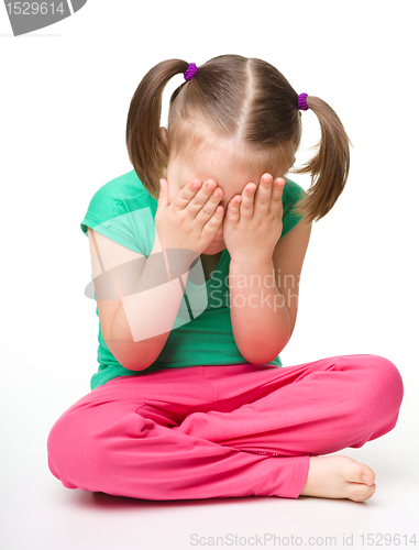 Image of Little girl is sitting on floor and crying